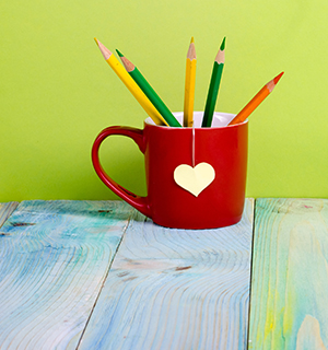 Red coffee mug filled with colored pencils